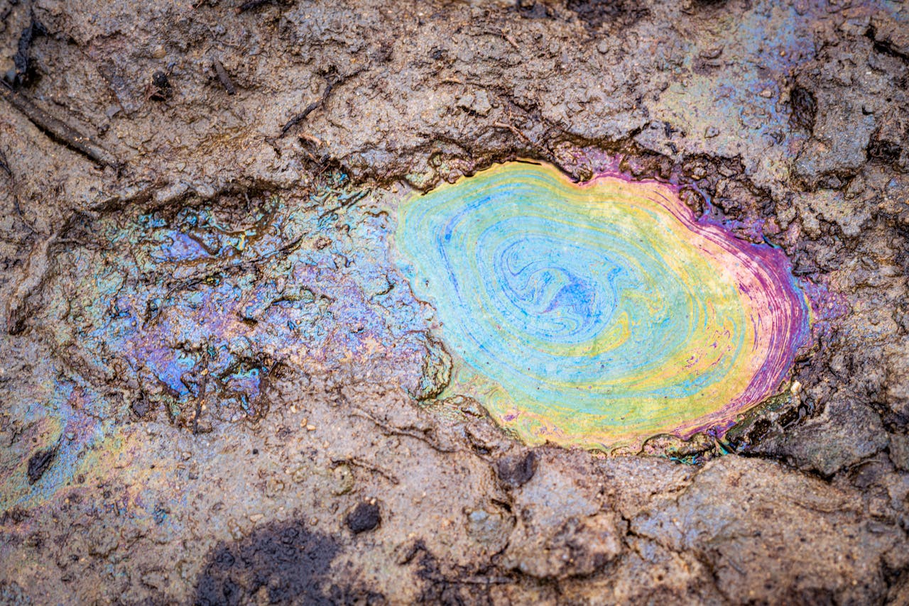 Vibrant rainbow colors on oil spill on muddy terrain in Bonny, Nigeria.
