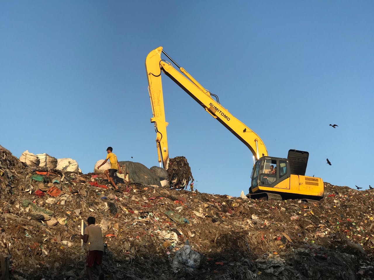 Excavator operating at a landfill in Chattogram, Bangladesh, highlighting environmental concerns.