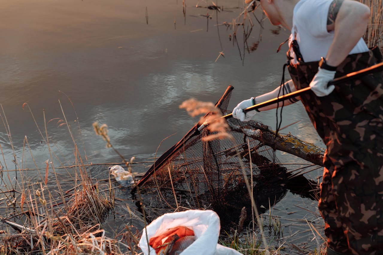 Person cleaning lake with net, promoting environmental awareness and conservation.